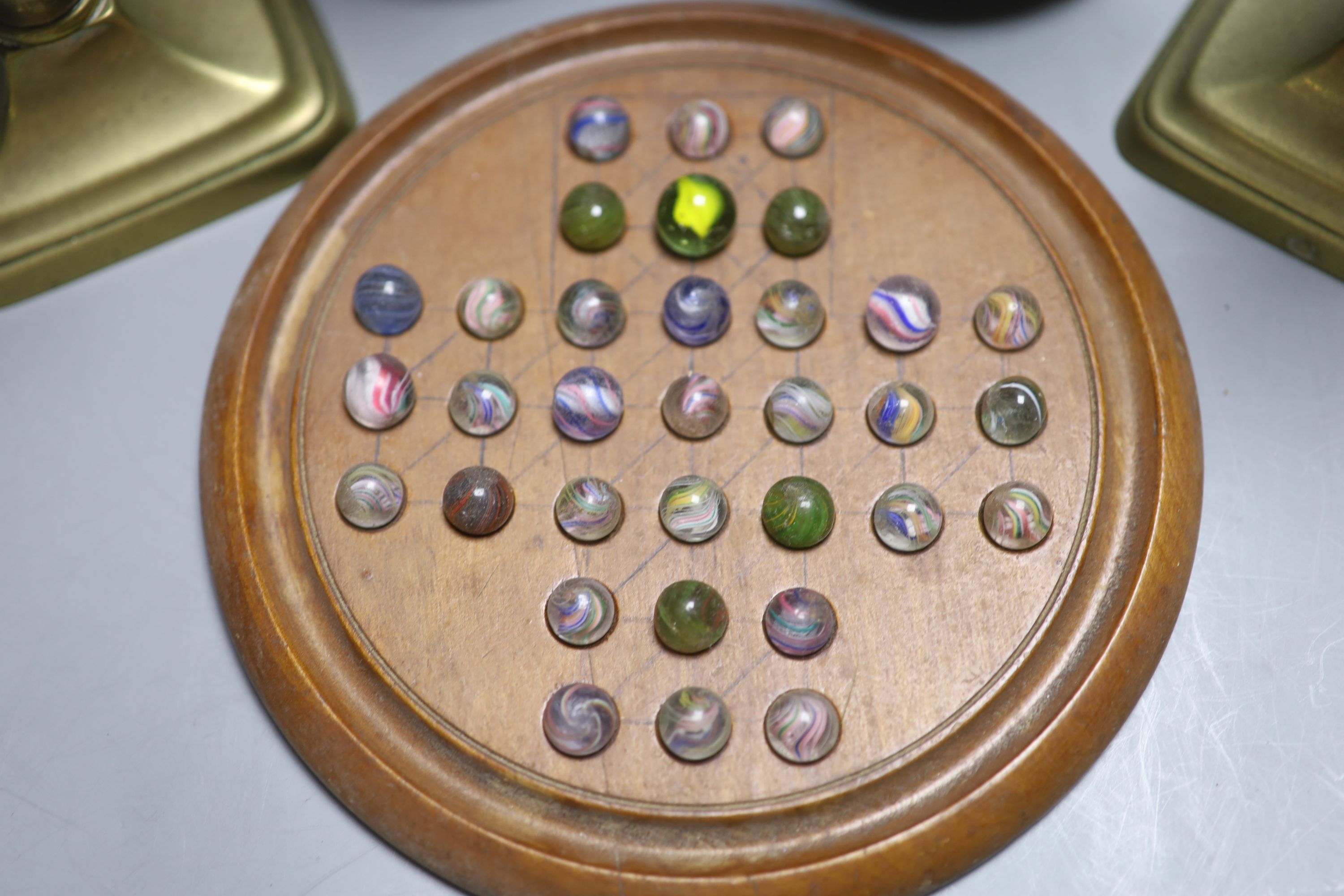 Two pairs of brass candlesticks and a solitaire board with marbles
